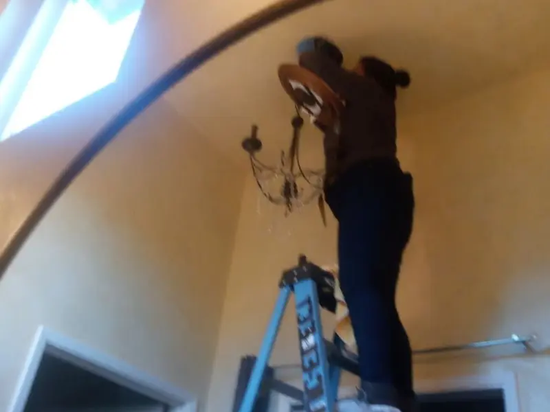 Electrician installing a chandelier in a Toledo residence